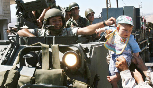جندي لبناني يلاعب طفلاً لدى دخول الجيش إلى بلدة حولا  (أ ب)