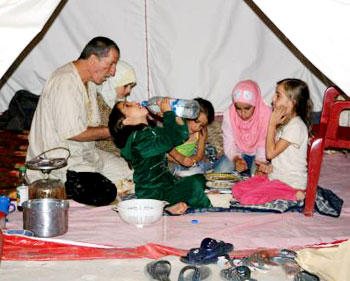 عائلة تتناول الإفطار في قرية دبين الجنوبية داخل خيمة بالقرب من منزلها المدمّر (رويترز)