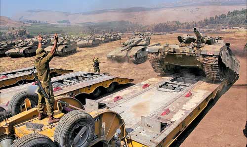 جنود إسرائيليون يشحنون دبابة شمال الاراضي المحتلة أمس (أ ب)