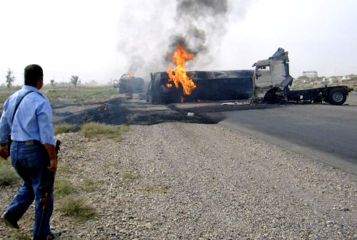 شرطي عراقي ينظر الى صهريج لنقل الوقود يحترق نتيجة هجوم بالعبوات في سامراء شمال بغداد أمس (رويترز)