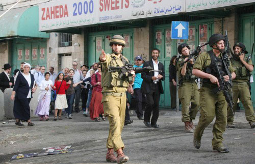 جنود إسرائيليون يخلون شوارع الخليل لمرور مستوطنين يهود أمس (رويترز)