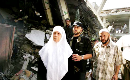 أم نضال أمام منزلها الذي قصفه الاحتلال في غزة أمس (رويترز)