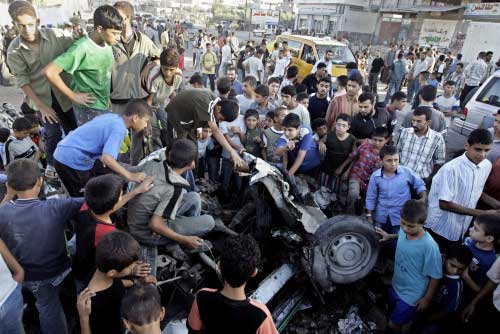 فلسطينيون يتجمعون حول سيارة استهدفها القصف الإسرائيلي في غزة أول من أمس (أ ب)