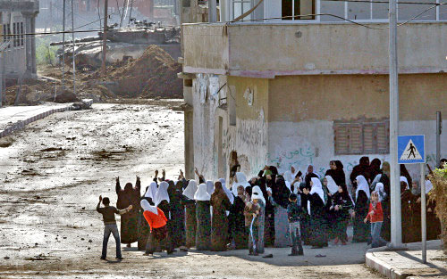 فلسطينيات يتحدين دبابة إسرائيلية أثناء مشاركتهن في فك الحصار عن مسجد النصر في بيت حانون أمس (أ ف ب)