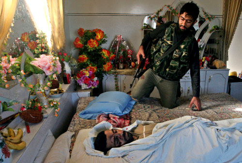 مقاوم من «حماس» قرب جثمان الشهيد أيمن حسنين في منزله في غزة أمس (أ ب)