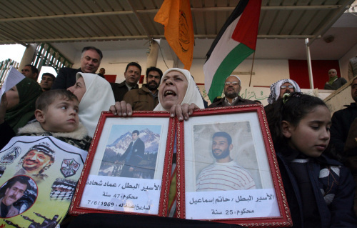 فلسطينية تحمل صوراً لأسرى أمام مقر الصليب الأحمر في غزة أمس (أ ف ب)