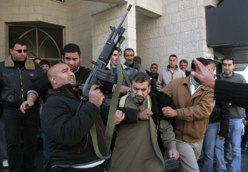 مقاتل من «فتح» يطلق النار في الهواء أثناء اختطاف قيادي من «حماس» في نابلس أمس (أ ب)