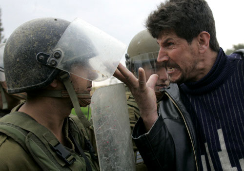 فلسطيني يصرخ في وجه جندي إسرائيلي خلال احتجاج ضدّ الجدار الفاصل في بلعين أمس (أ ب)