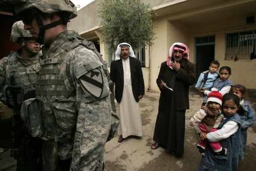 أفراد عائلة عراقيّة ينتظرون أثناء قيام جنود الاحتلال بتفتيش منزلهم في الموصل أمس (موريسيو ليما - أ ف ب)