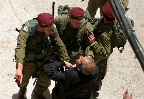 جنود الاحتلال يعتقلون فلسطينيّاً في الخليل أمس (عبد هشملون - إي بي أي)
