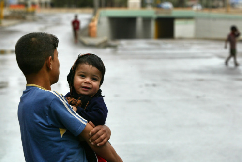 فتى عراقي يحمل أخاه في أحد الشوارع الخالية في وسط بغداد أمس (أحمد الربيعي - أ ف ب)