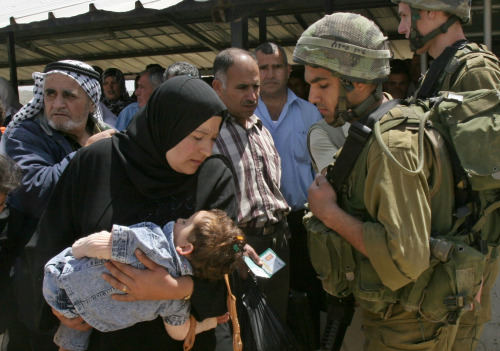 جندي للاحتلال يتفقّد أوراق فلسطينيّين عند نقطة الحوارة في نابلس أمس (ناصر إشطايه - أ ب)