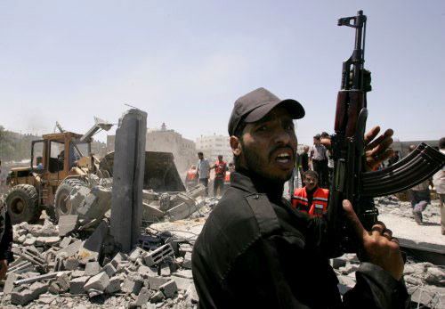 مسلّح من «حماس» على أنقاض مبنى القوة التنفيذية أول من أمس في غزة (محمد سالم - رويترز)