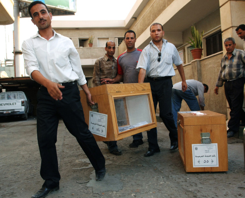 موظّفون مصريون يحملون صناديق الاقتراع في القاهرة الاثنين الماضي (محمد الساحتي - أ ب)