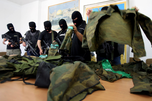 ملثّمون من «فتح» يعرضون بزات عسكرية وجدوها في مركز لـ«حماس» في نابلس أمس (جعفر اشتي - أ ف ب)