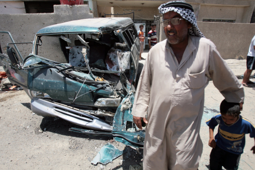 عراقي أمام بقايا سيارة انفجرت في بغداد أمس ( احمد الروبيعي - أ ف ب)