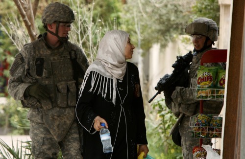 عراقية أمام جنديين أميركيين في بغداد أمس (نيكولا سوليك - رويترز)