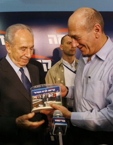 أولمرت يقدّم هدية إلى بيريز في ذكرى انطلاق حزب «كديما» في بتاح تكفا قرب تل أبيب أمس (كيفين فراير - أ ب)