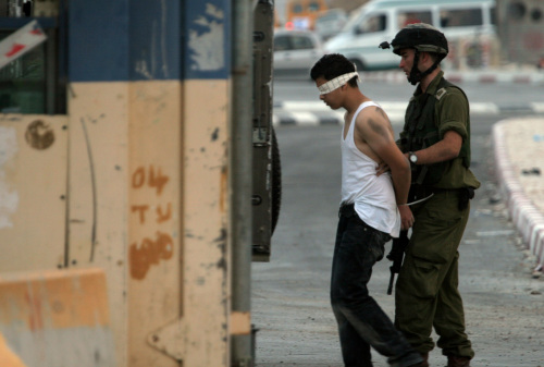 جندي إسرائيلي يعتقل فلسطينياً عند حاجز حوارة قرب نابلس في الضفة الغربية أمس (ناصر اشتيه - أ ب)
