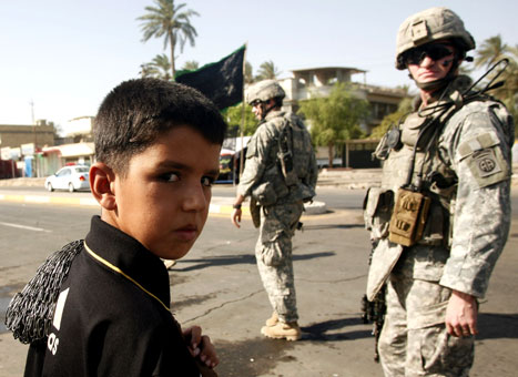صبي ينظر الى جنود أميركيين في الكاظمية شمال بغداد أمس (بيتر دايفد جوزيك - أ ب)