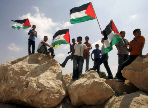 متظاهرون يلوحون بأعلام فلسطين وحركة “فتح” في جنوب الخليل أمس (نايف هشلمون - رويترز)