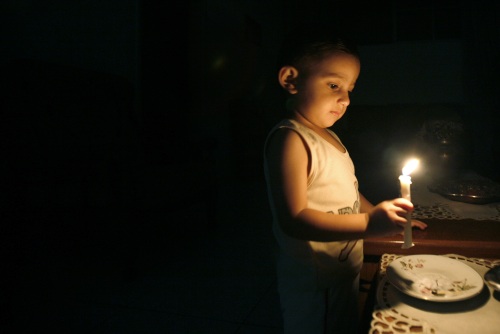 طفل فلسطيني يضيء شمعة بعد انقطاع التيار الكهربائي في غزة أمس (سهيب سالم - رويترز)