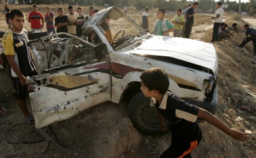 فلسطينيون حول السيارة المستهدفة في غزة أمس (ابراهيم أبو مصطفى - رويترز)