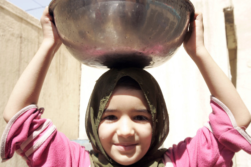 فتاة عراقية تحمل قدراً من الماء في مدينة الصدر أمس (صباح قرار - أ ف ب)