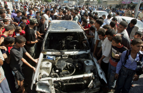 فلسطينيون يتجمعون حول سيارة تعرضت لقصف إسرائيلي في جنوب غزة أمس (خليل حمرا - أ ب)