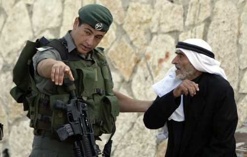 جندي إسرائيلي يمنع كهلاً فلسطينياً من الوصول إلى مسجد الأقصى أمس (موسى الساهر - أ ف ب)
