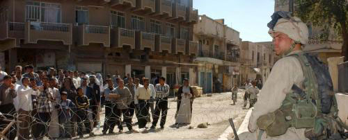 جندي أميركي يراقب عراقيّين قبل التحقيق معهم في أحد المعتقلات العراقية في بغداد (الأخبار)