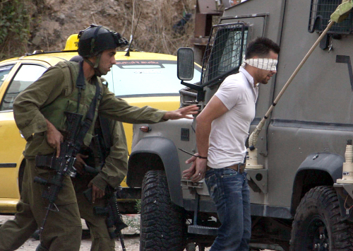 جندي إسرائيلي يقتاد معتقلاً فلسطينيّاً في نابلس أمس (جعفر عشطيّة - أ ف ب)
