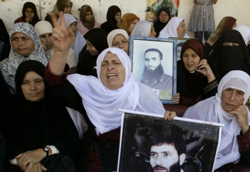 نسوة فلسطينيّات يحملن صور المعتقلين في السجون الإسرائيليّة في غزّة أمس (اسماعيل زايدة - رويترز)