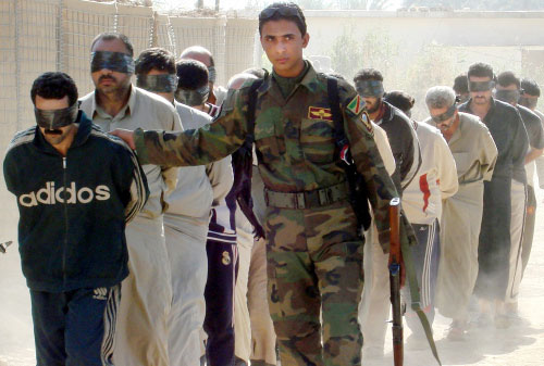 جندي عراقي يقتاد معتقلين في بعقوبة أمس (أ ب)