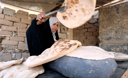 امرأة عراقية تخبز في أحد المتاجر في بغداد أمس (علي السعدي ـ ا ف ب)