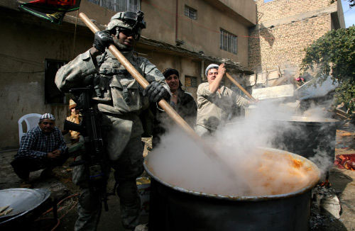 جندي أميركي يساعد عراقيّين في إعداد الهريسة في بغداد أمس (جويل صمد ـ أ ف ب)