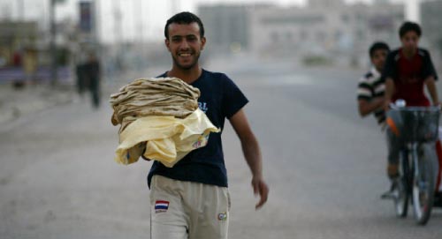 عراقي يحمل الخبز لعائلته في البصرة جنوب العراق أمس (عصام السوداني ـ أ ف ب)