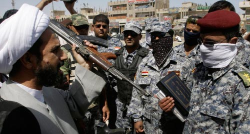 ممثل مقتدى الصدر الشيخ سلمان الفرج يتسلم سلاحاً من عناصر الشرطة العراقية في بغداد أمس ( كريم كاظم - أ ب)