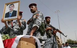 عناصر من قوات الأمن العراقية يرفعون صورة للمالكي في النجف أمس (علاء المرجاني ـ أ ب)