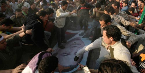 مصريون يدوسون صورة مبارك في منطقة المحلّة الكبرى (110 كيلومترات شمال القاهرة) أمس (ناصر نوري - رويترز)