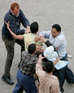 عناصر أمن مصريّون بزيّ مدني يعتدون على أحد متظاهري المحلّة الكبرى في 6 نيسان (ناصر نوري ــ رويترز)