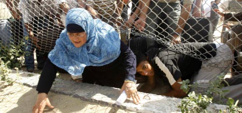 غزّاويّة تحاول عبور معبر رفح من تحت الأسلاك الشائكة أمس (محمد سالم ـــ رويترز)