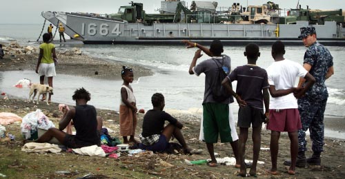 هايتيون يراقبون آلية أميركية على الشاطئ (ستيف إيرلي ـ أ ب)