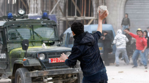 شاب فلسطيني يرمي حجراً على آليّة إسرائيليّة (أرشيف ــ رويترز)