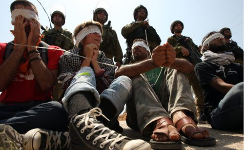 ناشطون من أجل السلام يعيدون تمثيل أحد مشاهد القهر اليوميّ في فلسطين المحتلّة (أرشيف ــ أ ف ب)