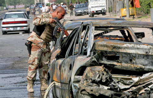 جندي عراقي يتفحص سيارة تم تفجيرها في بغداد امس (اب)
