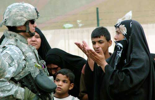 عراقية تتحدث الى جندي أميركي يشرف على توزيع مساعدات إنسانية في بغداد أمس (أ ب)