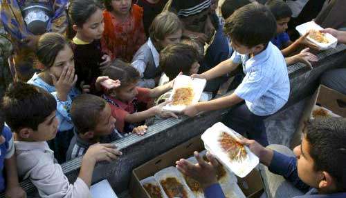 أطفال عراقيون يتسابقون للحصول على حصصهم من موائد الرحمن في مدينة كربلاء (رويترز)