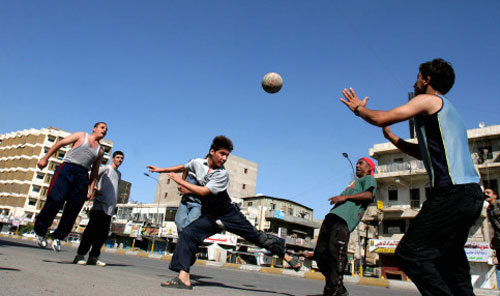 عراقيون يلعبون كرة القدم في أحد شوراع بغداد خلال إحدى الفسحات بين التفجيرات والاشتباكات أمس (أ ب)