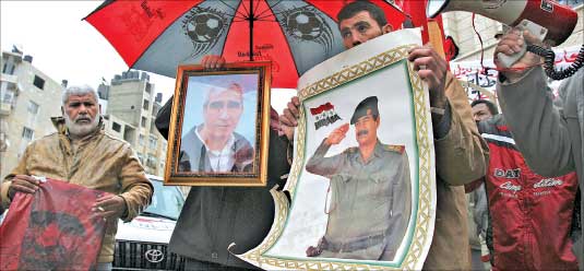 فلسطينيون يرفعون صورتي صدام وأحمد سعدات خلال احتجاج في نابلس في الضفة الغربية أمس (أ ب)
